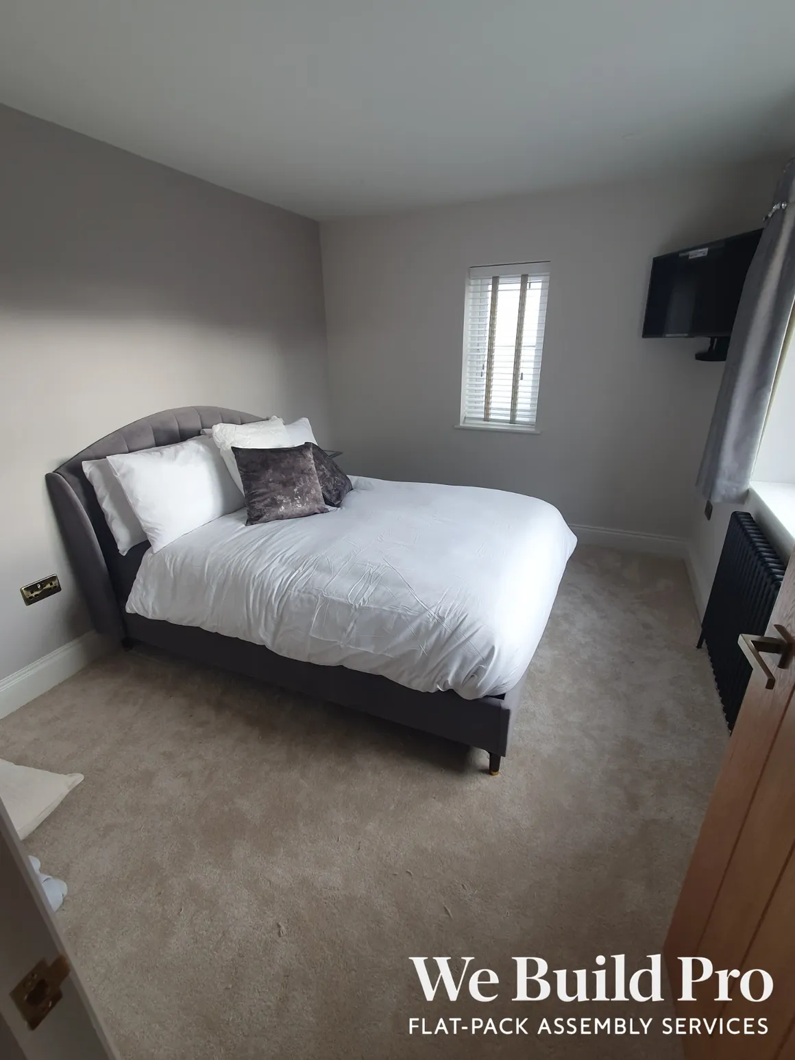 Minimalist bedroom with dark bed frame and wall-mounted TV