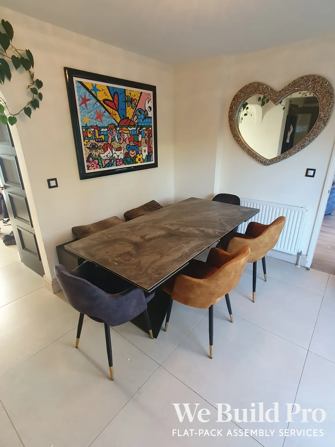 Stylish dining room with marble table, colorful chairs, and heart-shaped mirror