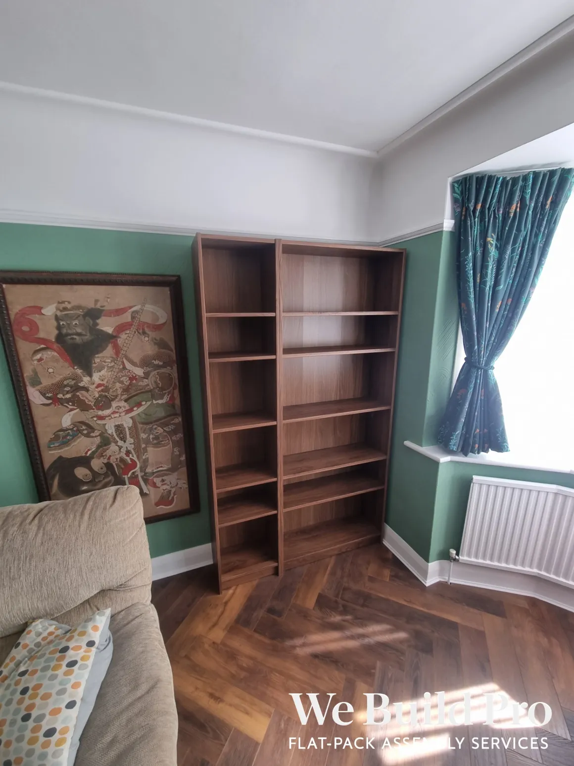 Living room with wooden bookshelves, green accent wall and Japanese artwork