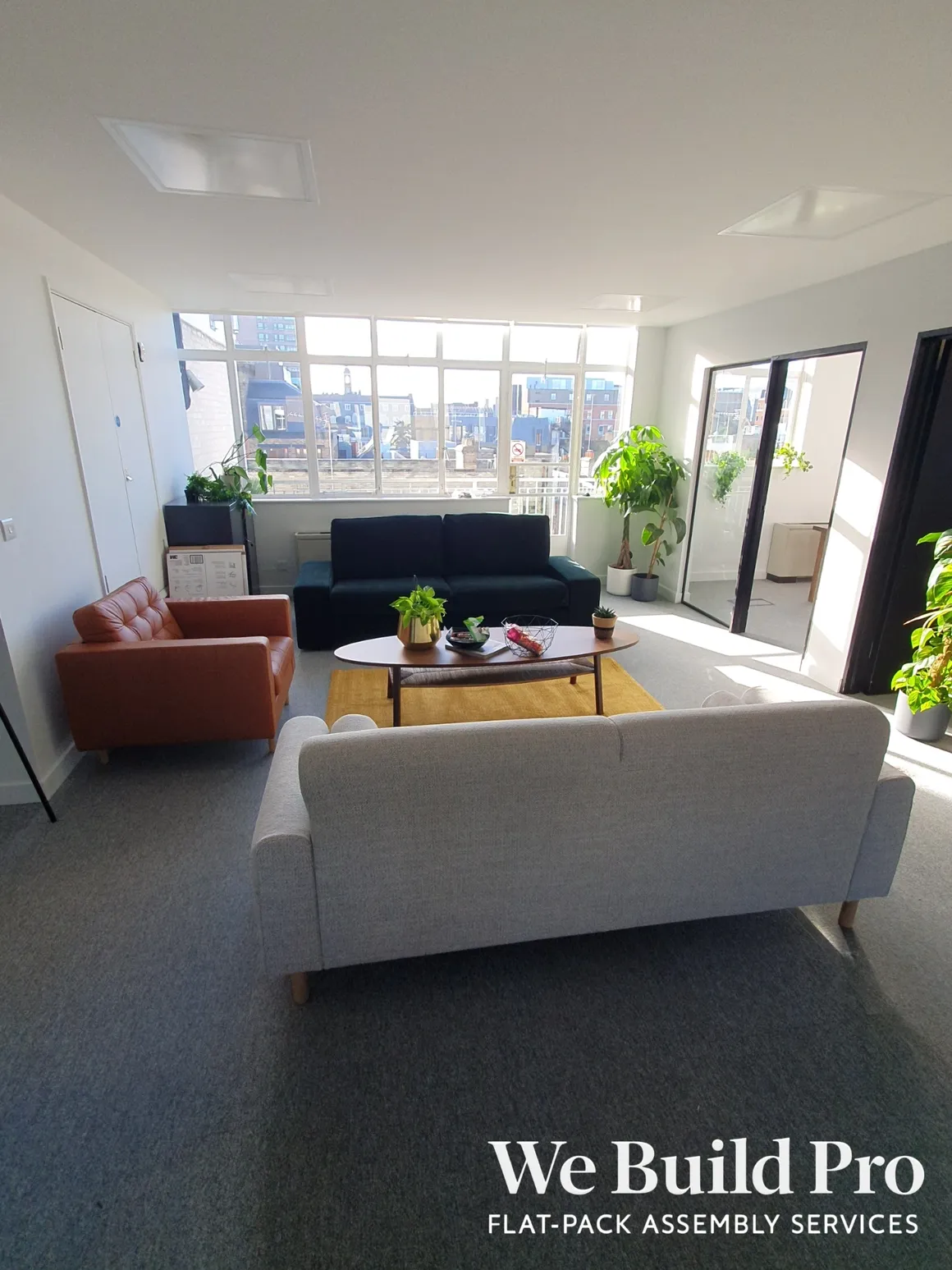 Modern office lounge with mixed seating, plants and city views