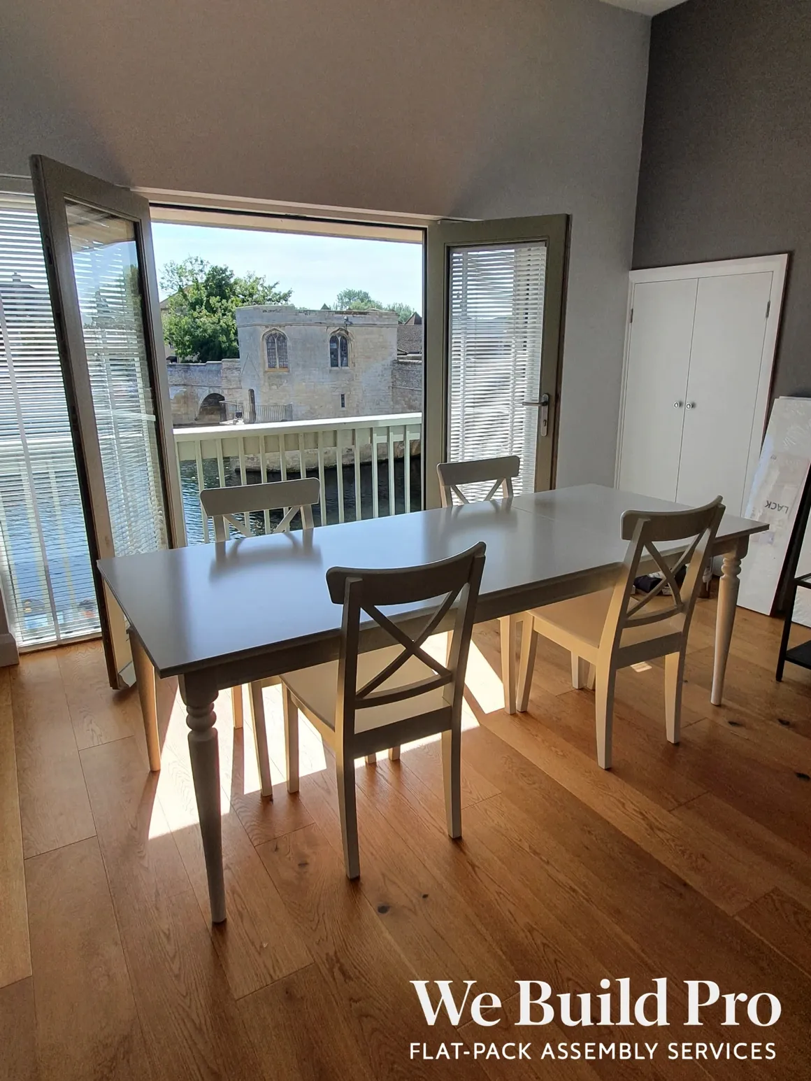 Dining room with dark wooden table, cross-back chairs and balcony views
