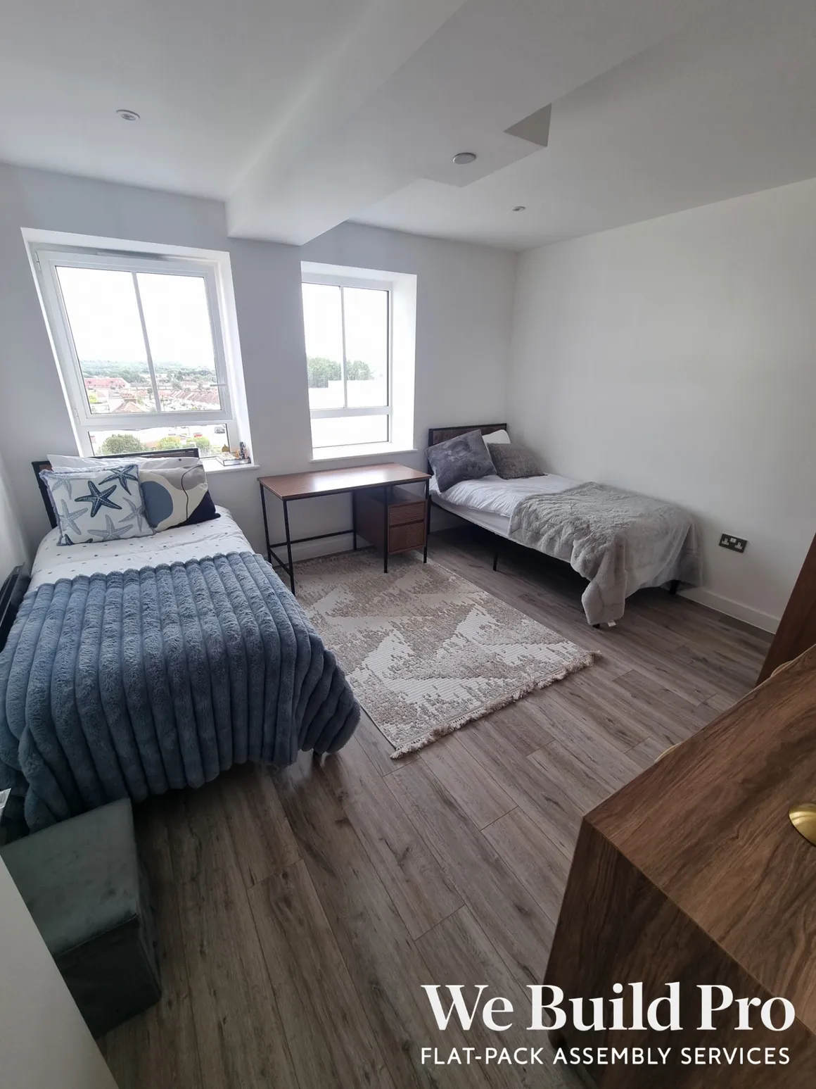 Modern twin bedroom with shared desk, large windows and wooden flooring