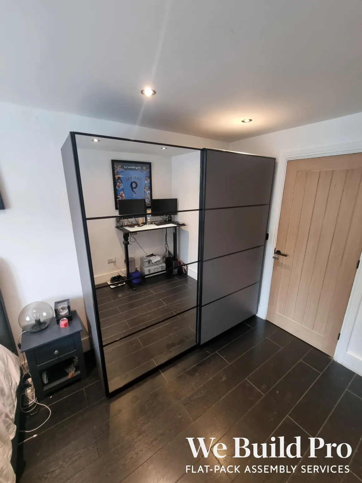 Modern sliding mirrored wardrobe with black frame and computer workstation