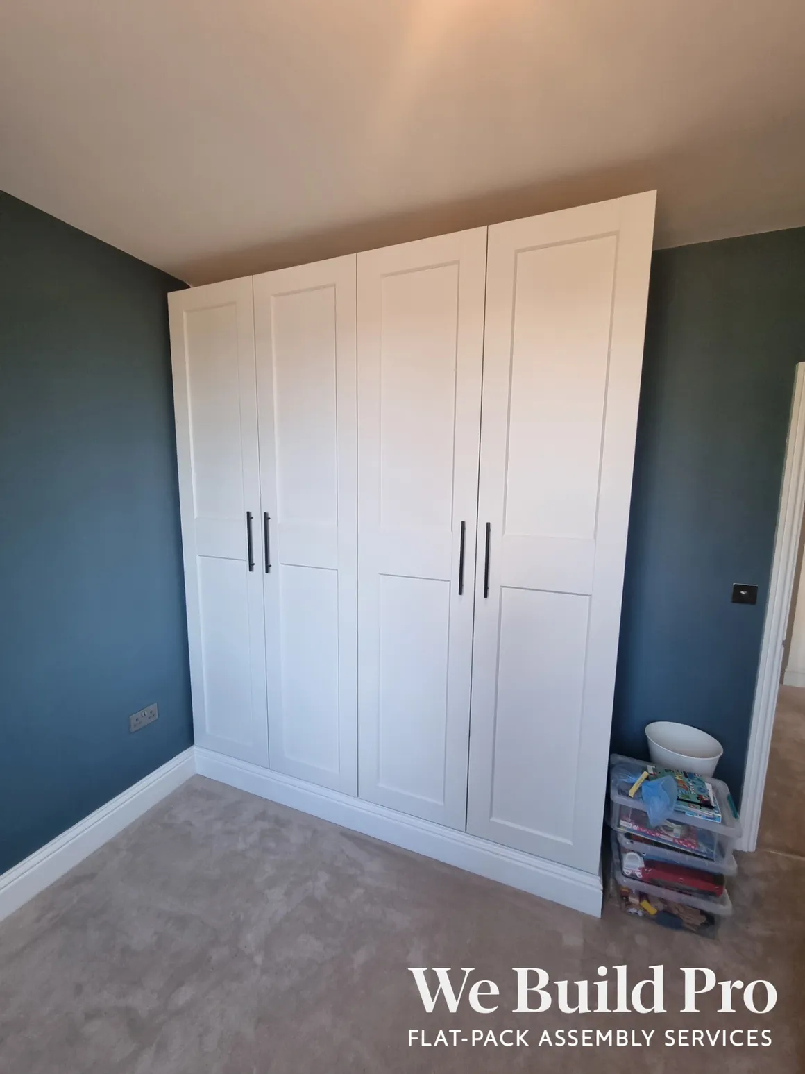 White fitted wardrobes with panel doors and black handles in blue bedroom